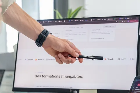 Un stylo OMIA désigne à l'écran la page « Des formations finançables. » du site OMIA.